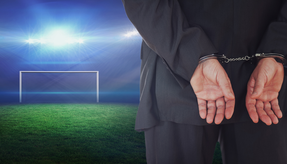Businessman,In,Handcuffs,Against,Football,Pitch,With,Bright,Lights